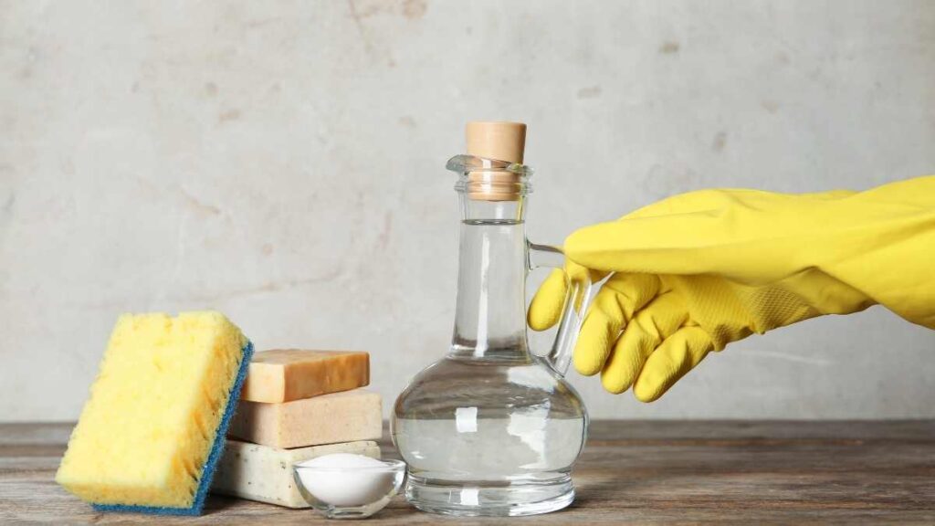 hand in yellow rubber glove picking up vinegar